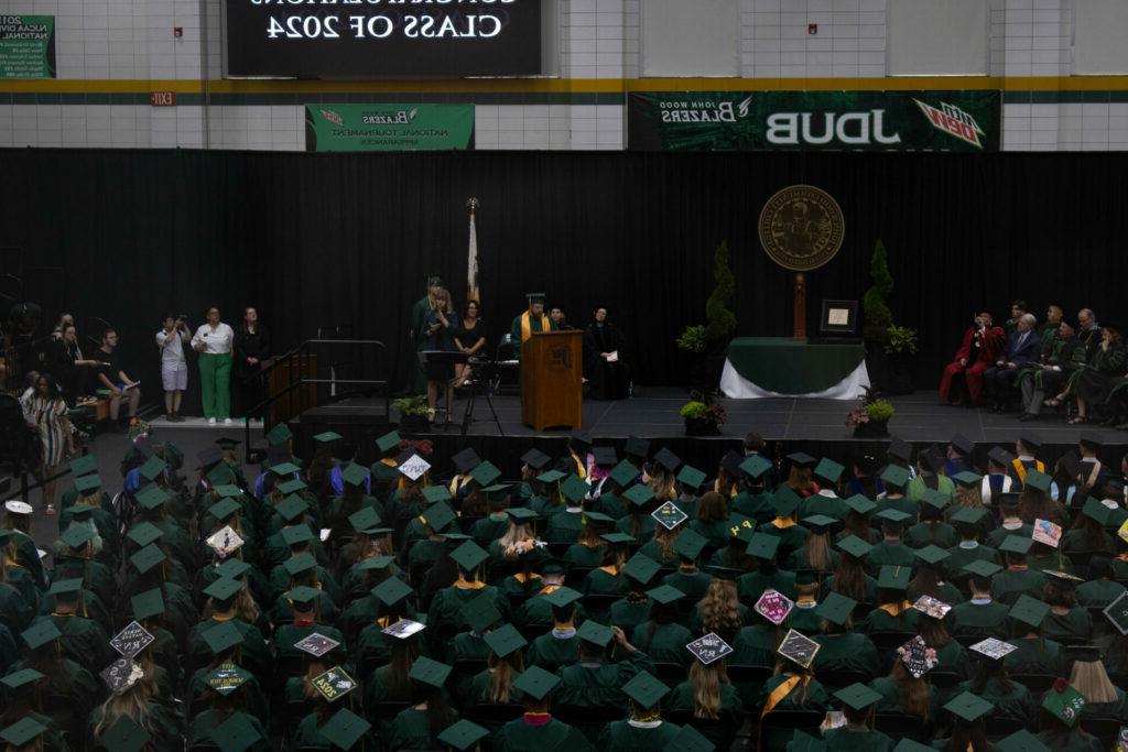 Graduates in caps and gowns listen to a speech presented